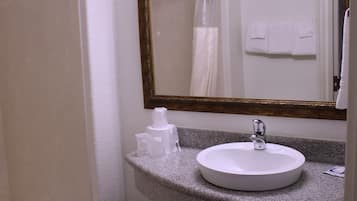 Un baño con un lavamanos blanco, un espejo con marco dorado y una toalla colgada en la pared.