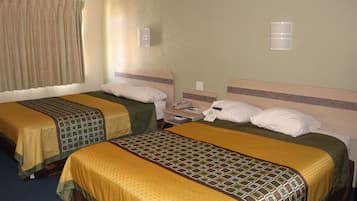 A hotel room with two beds, each with a patterned bedspread, a bedside table with a phone, and a wall-mounted light.