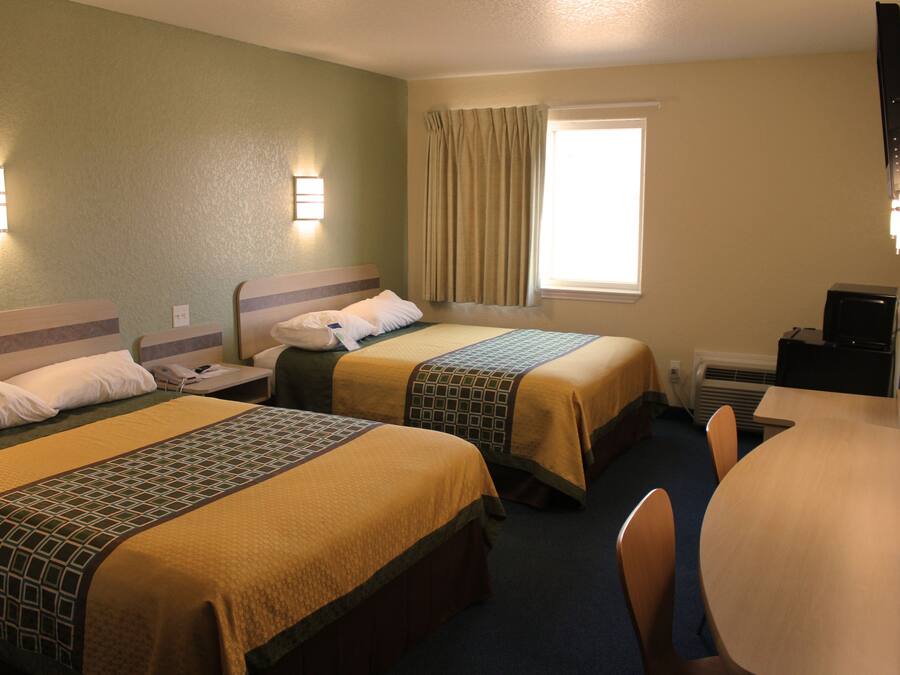 A hotel room with two beds, a desk, and a television.