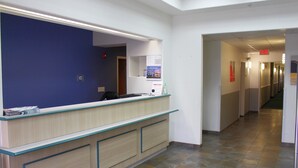 A reception desk with a blue wall, a counter with a light wood finish, and a tiled floor.