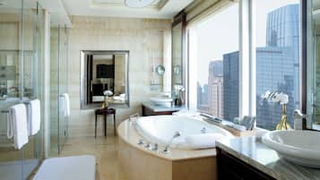 A modern bathroom with a large bathtub, a glass shower enclosure, and a view of the cityscape.