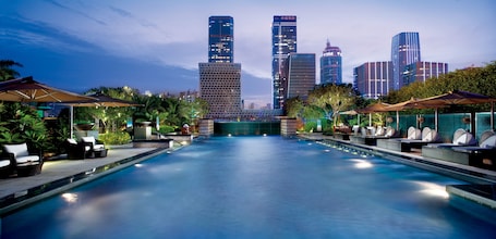 Una piscina al aire libre, sombrillas, sillones reclinables de piscina