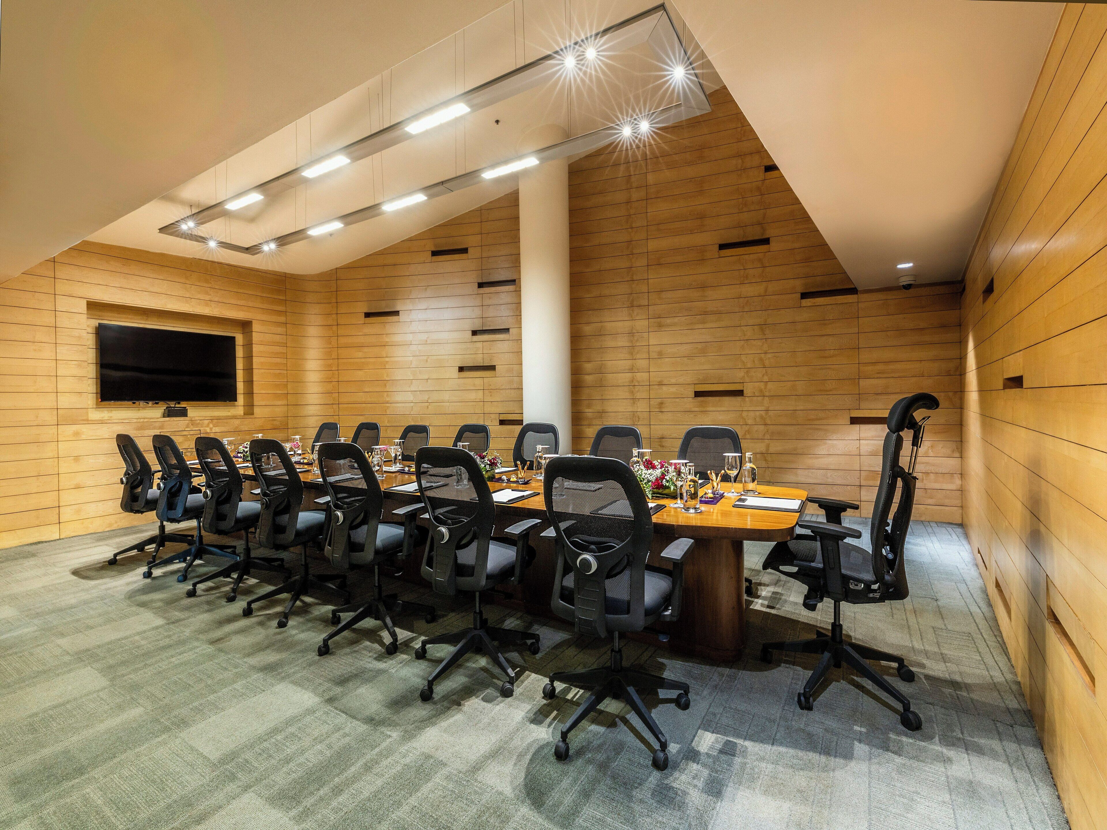 A ceiling with linear lighting fixtures and a wooden sloped ceiling.