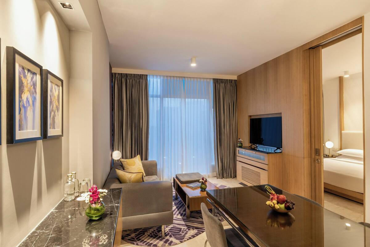 A hotel room with a sofa, a dining table, a TV, and a bed.