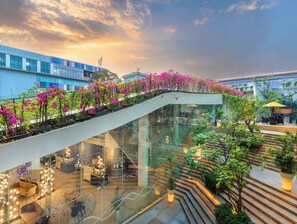 Um edifício moderno com escadaria de vidro, plantas internas e áreas de estar.
