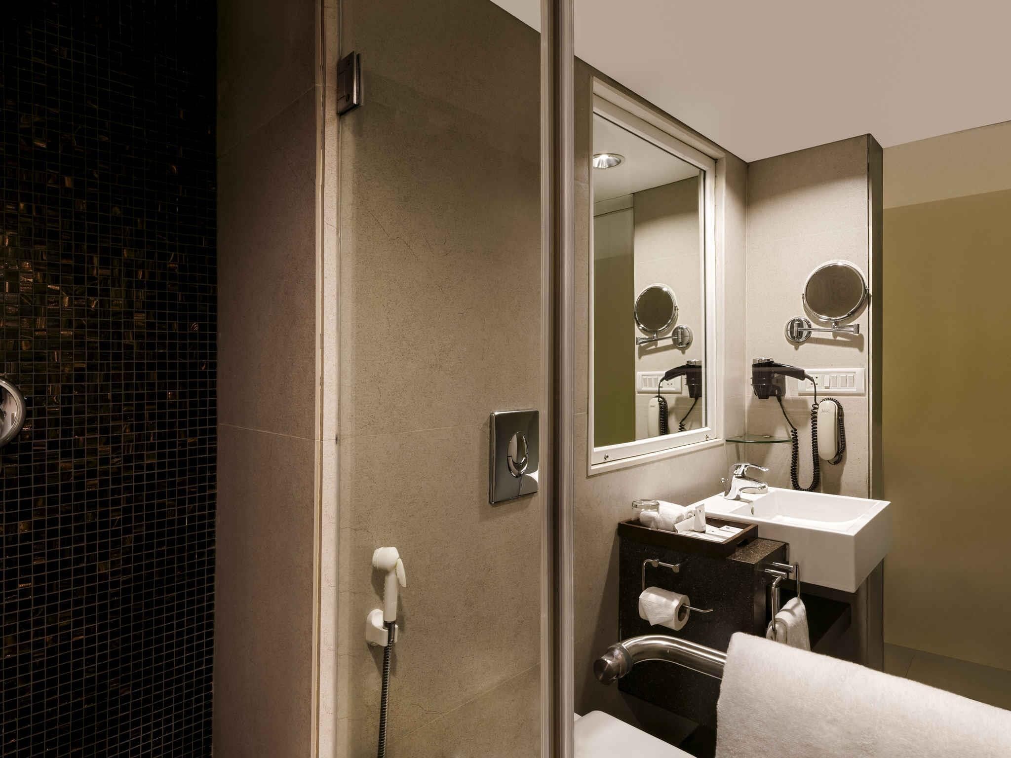 Une salle de bain équipée d’une douche, d’un lavabo, d’un miroir et d’un sèche-cheveux.