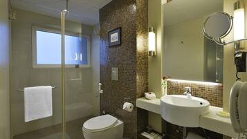 A modern bathroom with a glass-enclosed shower, a toilet, a sink, and a large mirror.