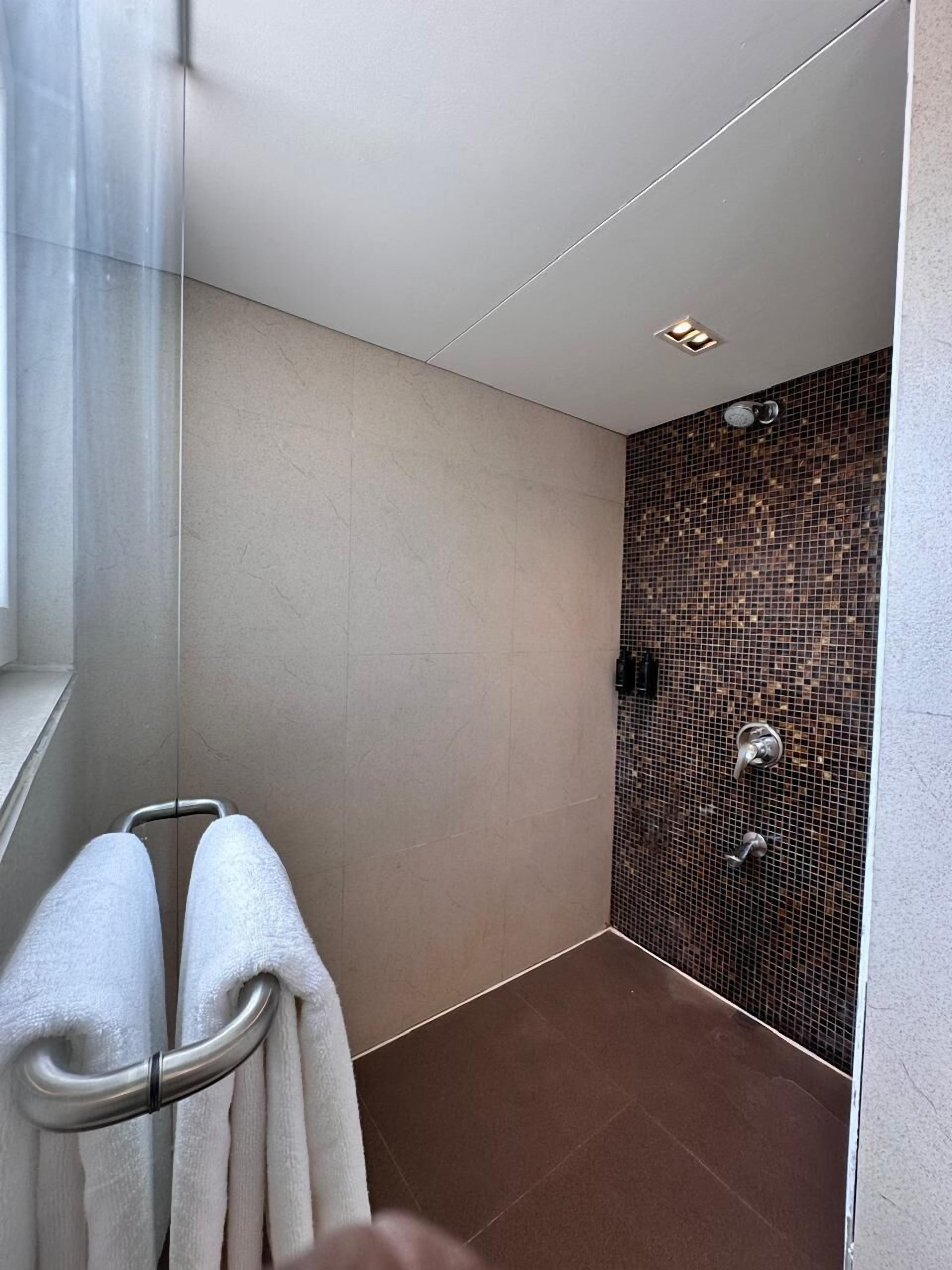 Een moderne badkamer met een douchecabine van glas, een handdoekrek en een betegelde douchemur.