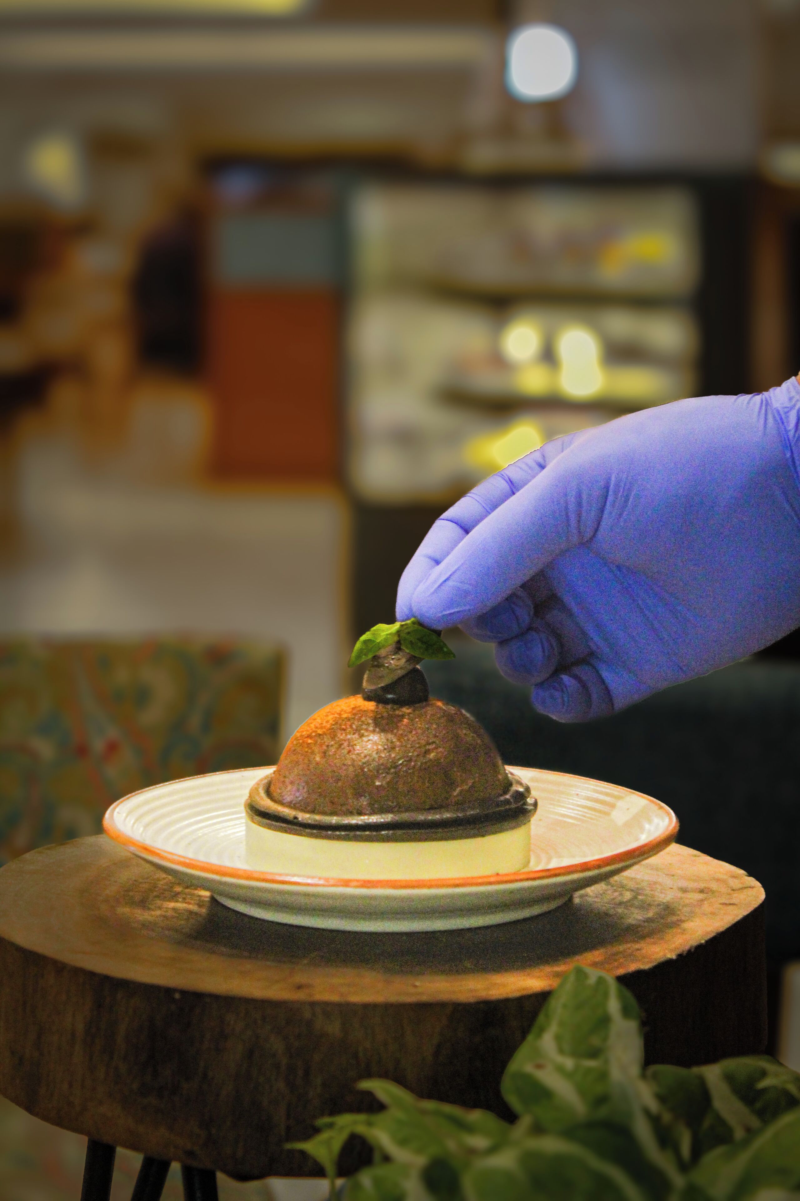 A dessert on a plate with a hand wearing a glove.
