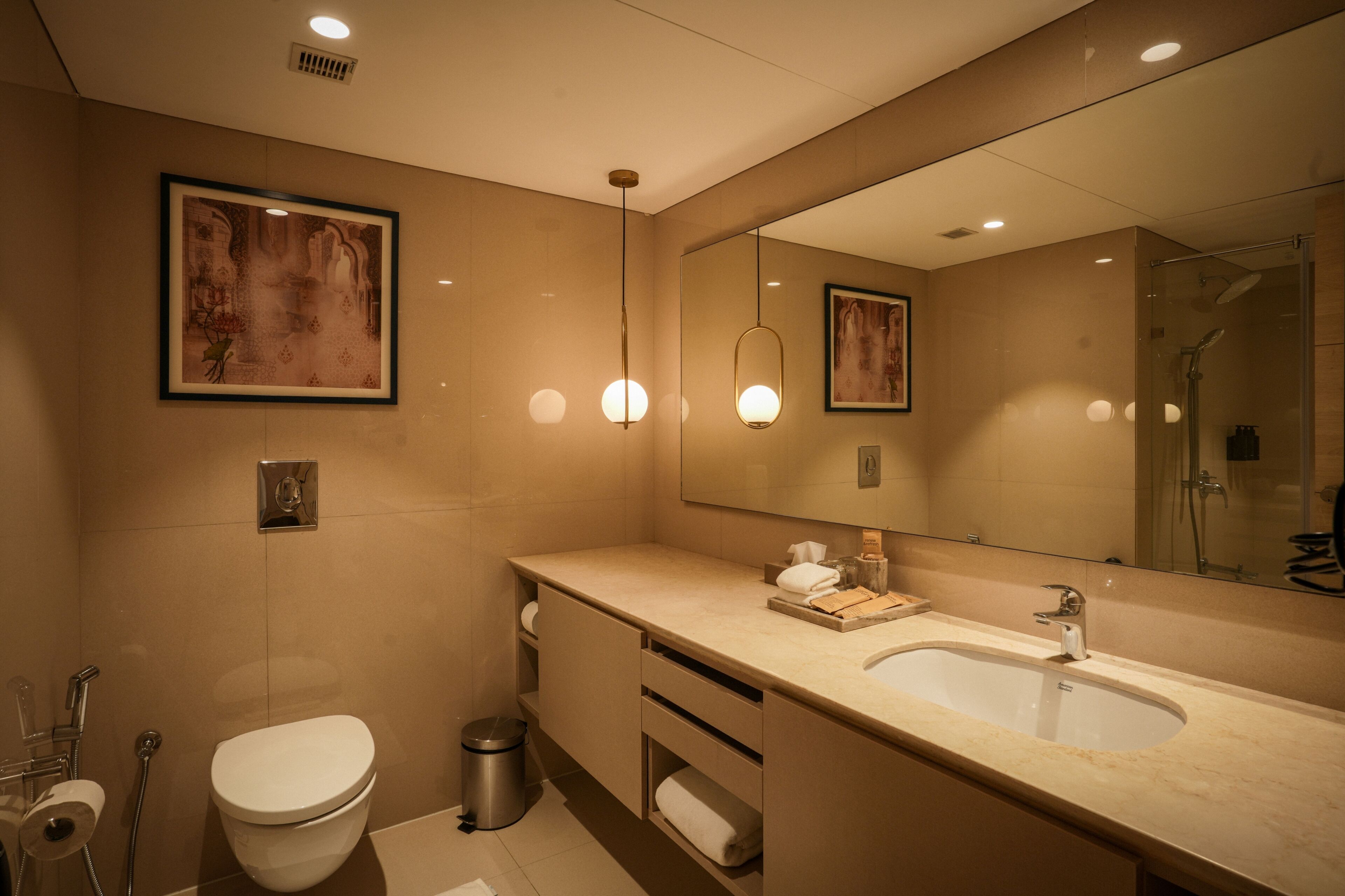 Un bagno moderno con uno specchio grande, un lavandino, un water e una doccia.