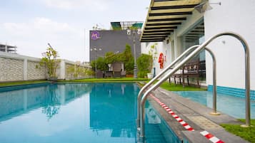 Una piscina al aire libre, sillones reclinables de piscina