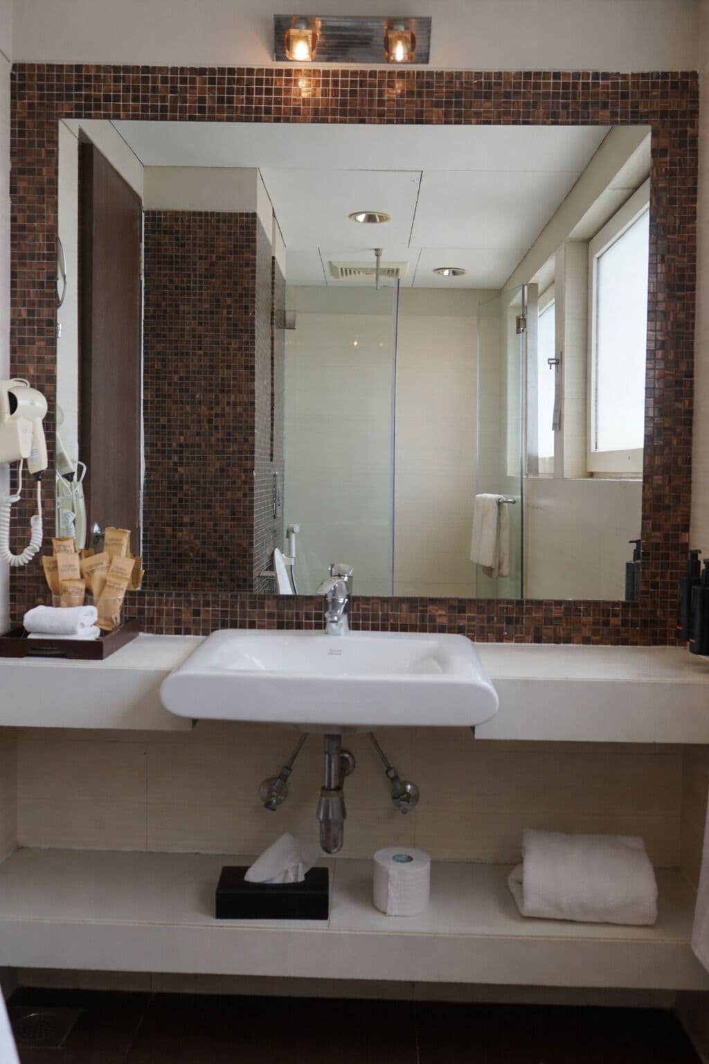 A bathroom with a large mirror, a sink, and a shower area.