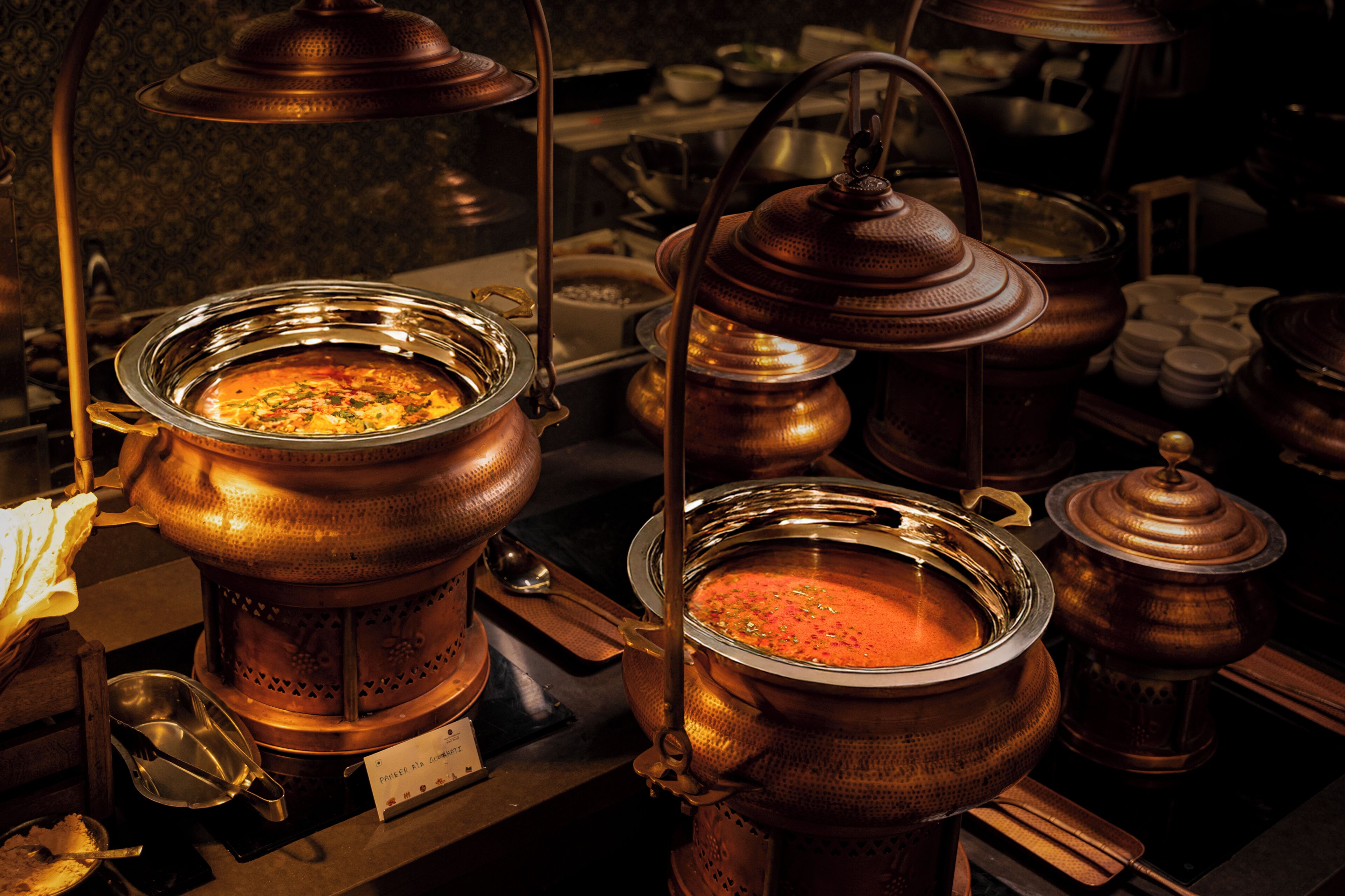 Una cocina con utensilios de cobre, incluyendo ollas y sartenes, y una estufa.