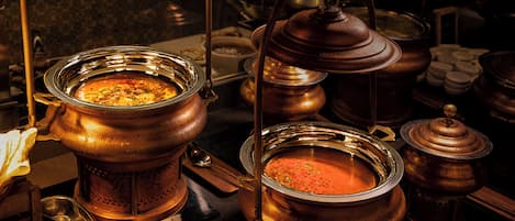 Una cocina con utensilios de cobre, incluyendo ollas y sartenes, y una estufa.