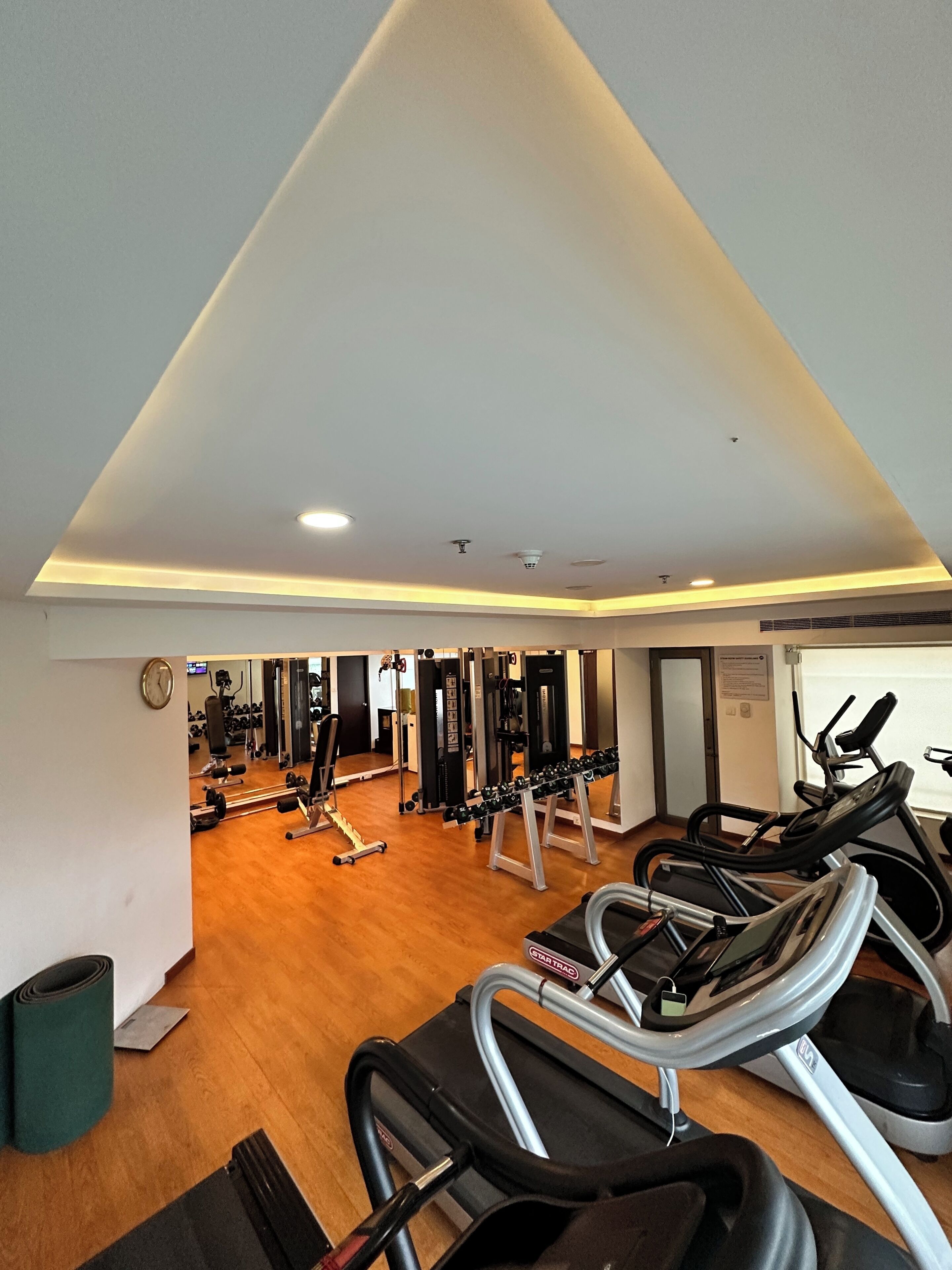 A gym with treadmills, weight machines, and a wooden floor.