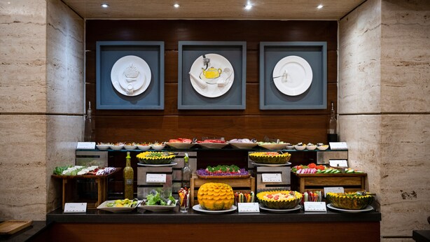 A buffet with various food items and a wall with framed plates.