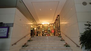 A marble staircase with floral decorations leading to a reception area with a glass partition and a sign indicating a ball room.