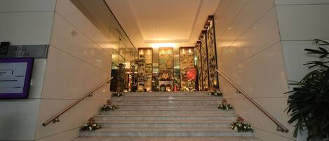 A marble staircase with floral decorations leading to a reception area with a glass partition and a sign indicating a ball room.