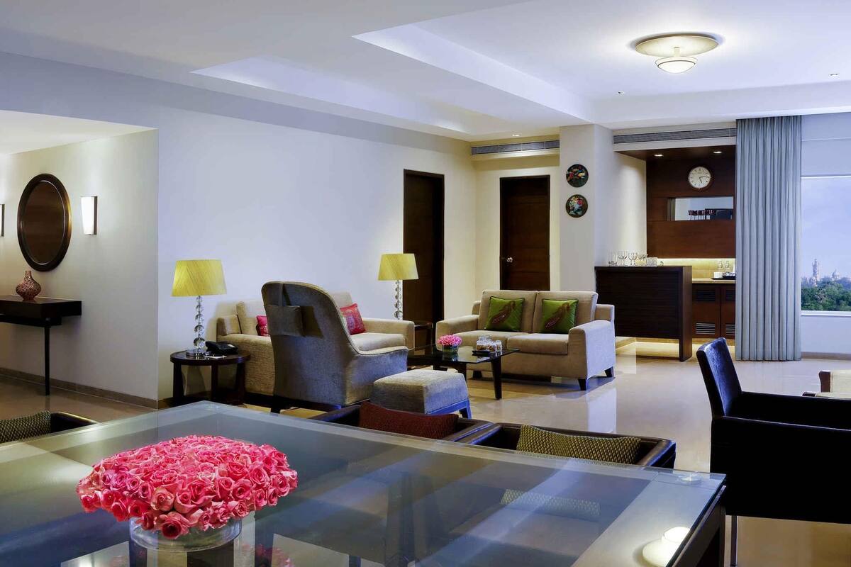 A modern living room with a glass dining table, sofas, a coffee table, and a fireplace.