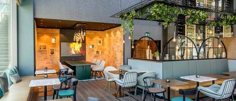 Un restaurante moderno con un rincón de estar acogedor, una chimenea y una vinoteca visible al fondo.