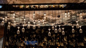 En bardisk med hängande lampor i glas och ett stort urval av spritflaskor utställda på hyllor.