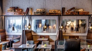 Een modern interieur met lederen zitplaatsen, tafels en vintage koffers op planken.