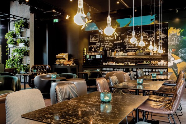 Un interior de restaurante moderno con asientos de cuero, lámparas colgantes y un menú en una pizarra.