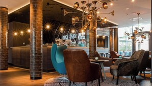 A modern interior with high ceilings, exposed brick columns, and a bar area with seating.