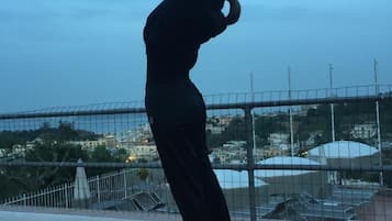 A person performing a yoga pose on a rooftop terrace with a cityscape in the background.