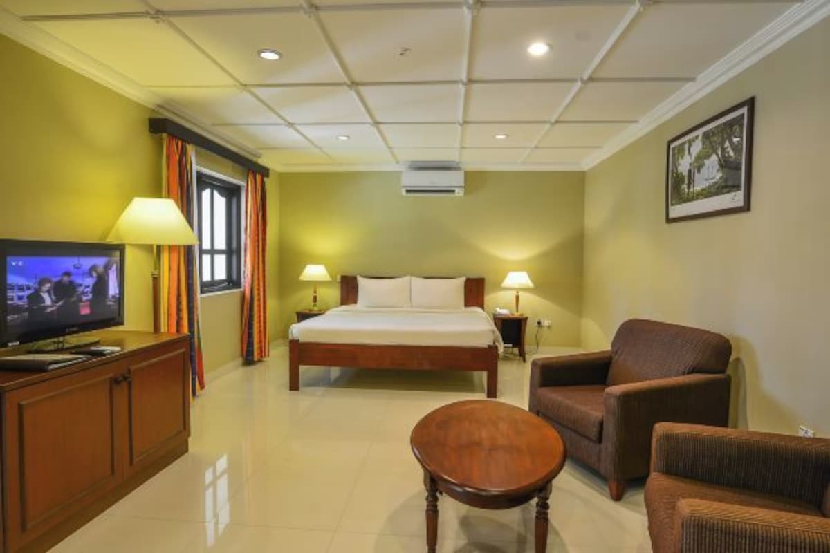 A hotel room with a bed, a television, a desk, and two chairs.