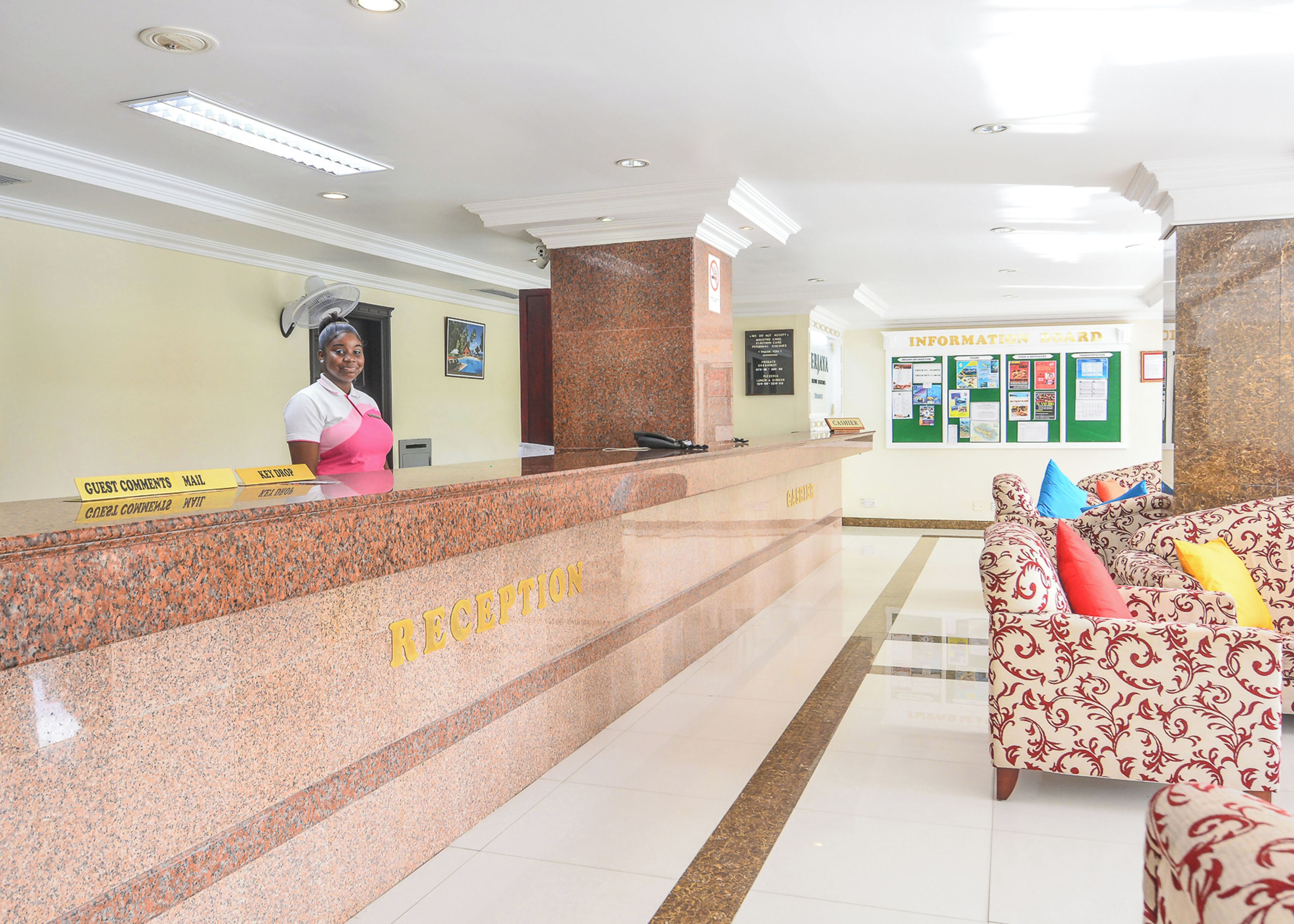 A reception area with a marble counter, a receptionist, and a bulletin board.