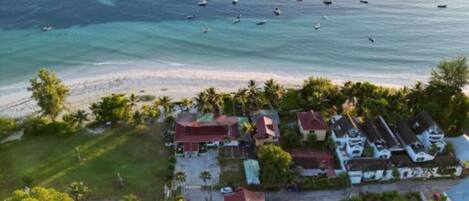 Vista aérea de una zona residencial costera con casas, una playa y barcos en el agua.