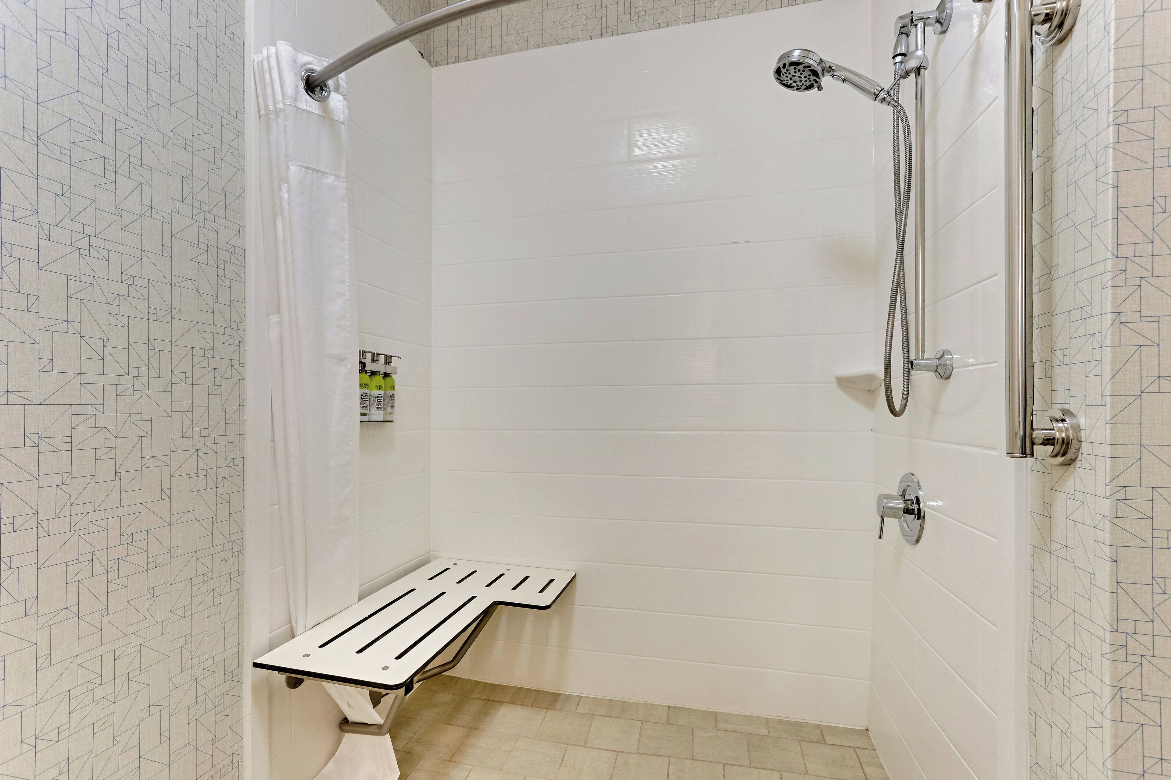 Une douche équipée d’un pommeau de douche à main, d’un flexible de douche et d’un porte-savon ou d’un étagère pour les produits de douche.