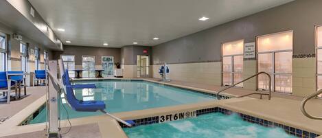 An indoor swimming pool with a 3ft 6in depth, surrounded by blue chairs and a lifeguard station.