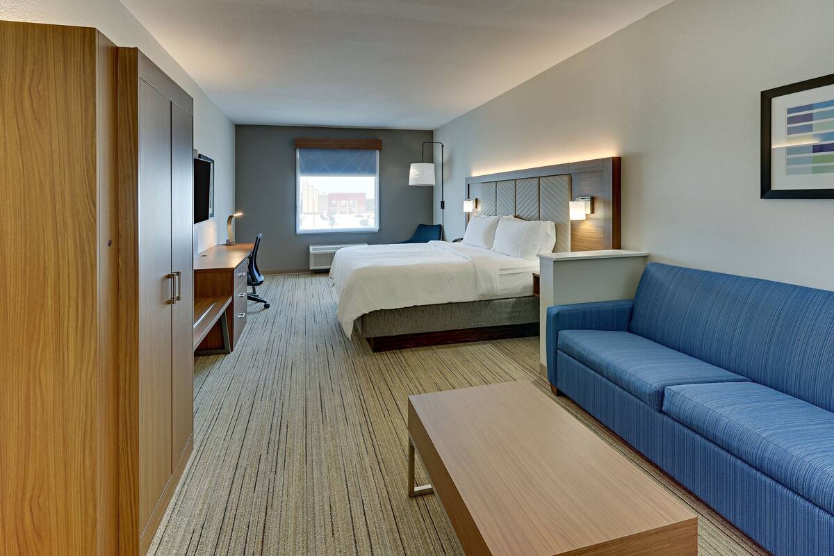 A hotel room with a bed, a sofa, a desk, and a wardrobe.