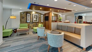 Un hall d’entrée moderne agrémenté d’un mur en pierre, d’un canapé, de fauteuils et d’une petite table.