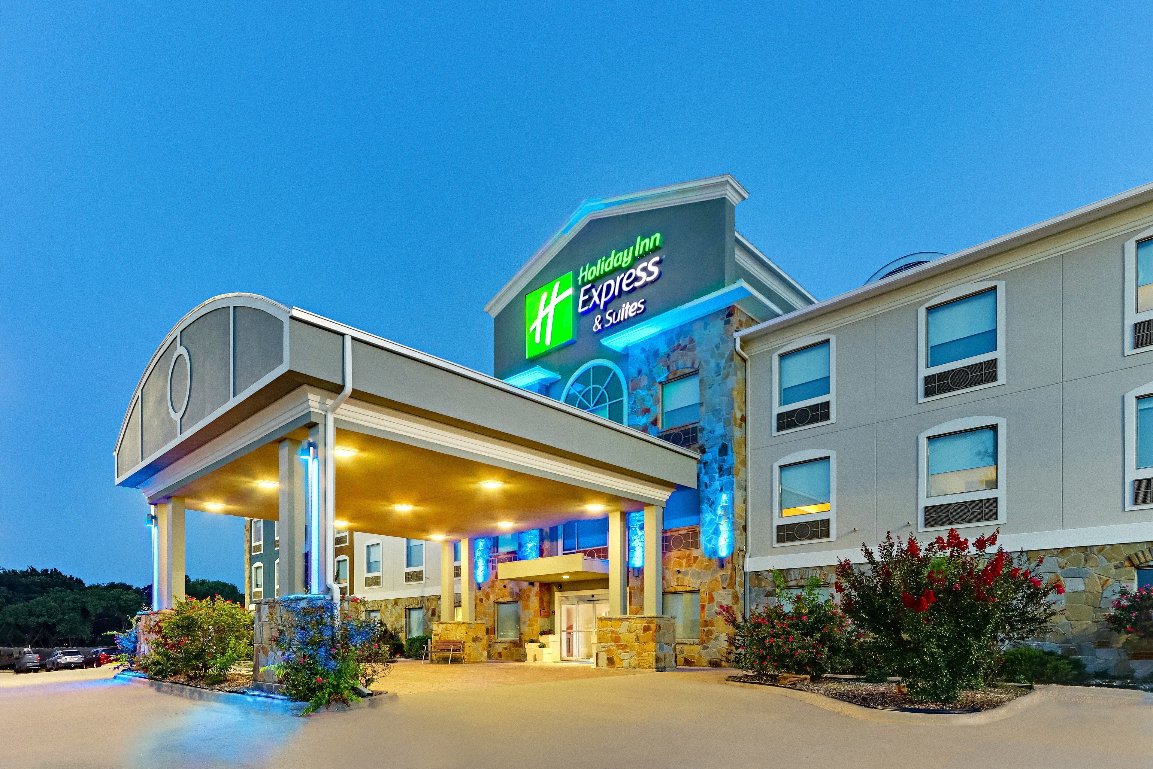 A Holiday Inn Express & Suites with a stone facade, a covered entrance, and a parking lot.