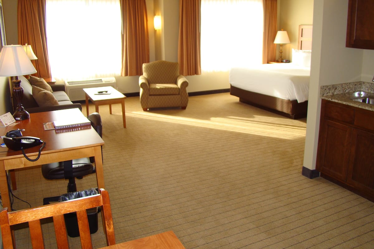 A hotel room with a bed, a desk with a telephone, a chair, a sofa, and a small table.