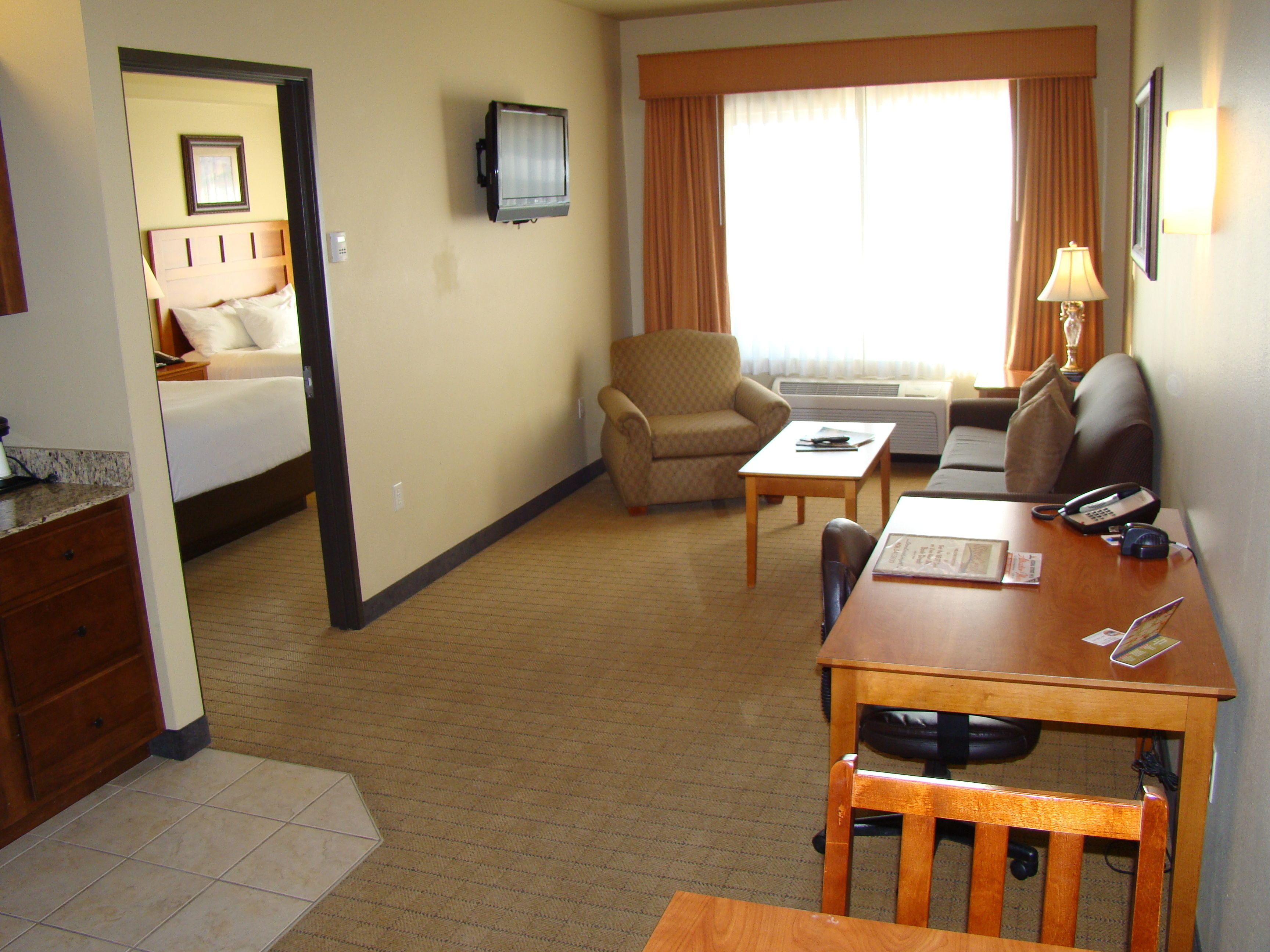 A hotel room with a bed, a desk, a chair, a television, and a window with curtains.