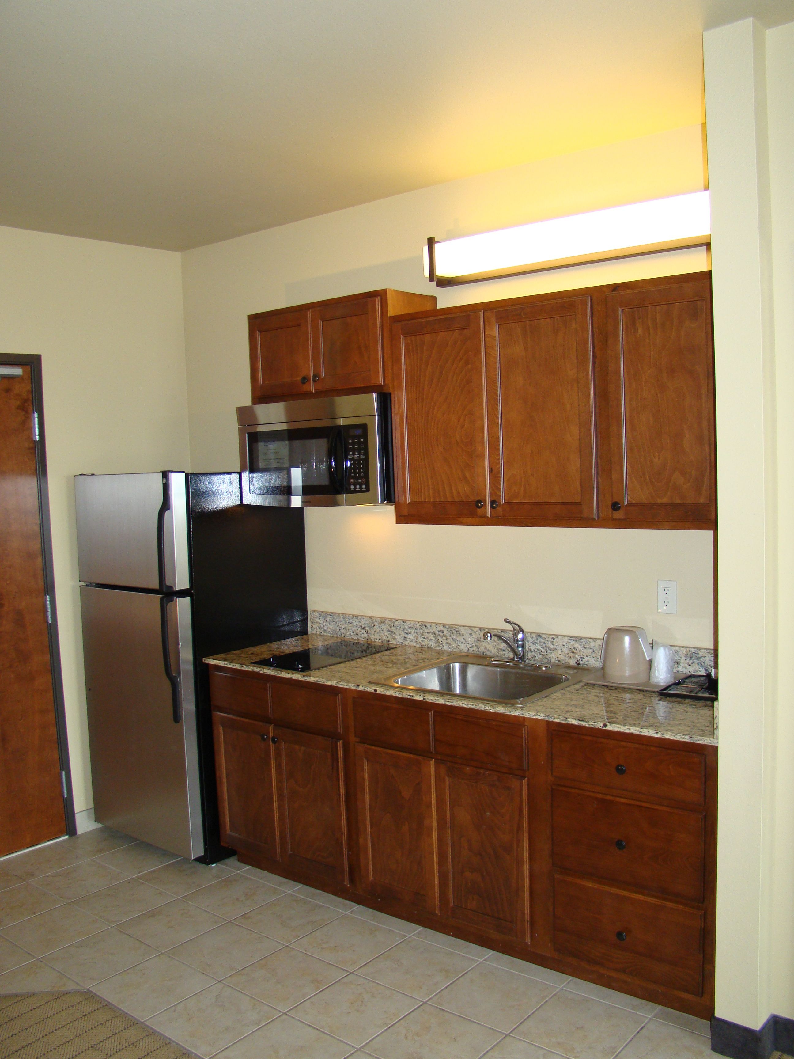 A kitchen with wooden cabinets, stainless steel appliances, granite countertops, and a built-in microwave.