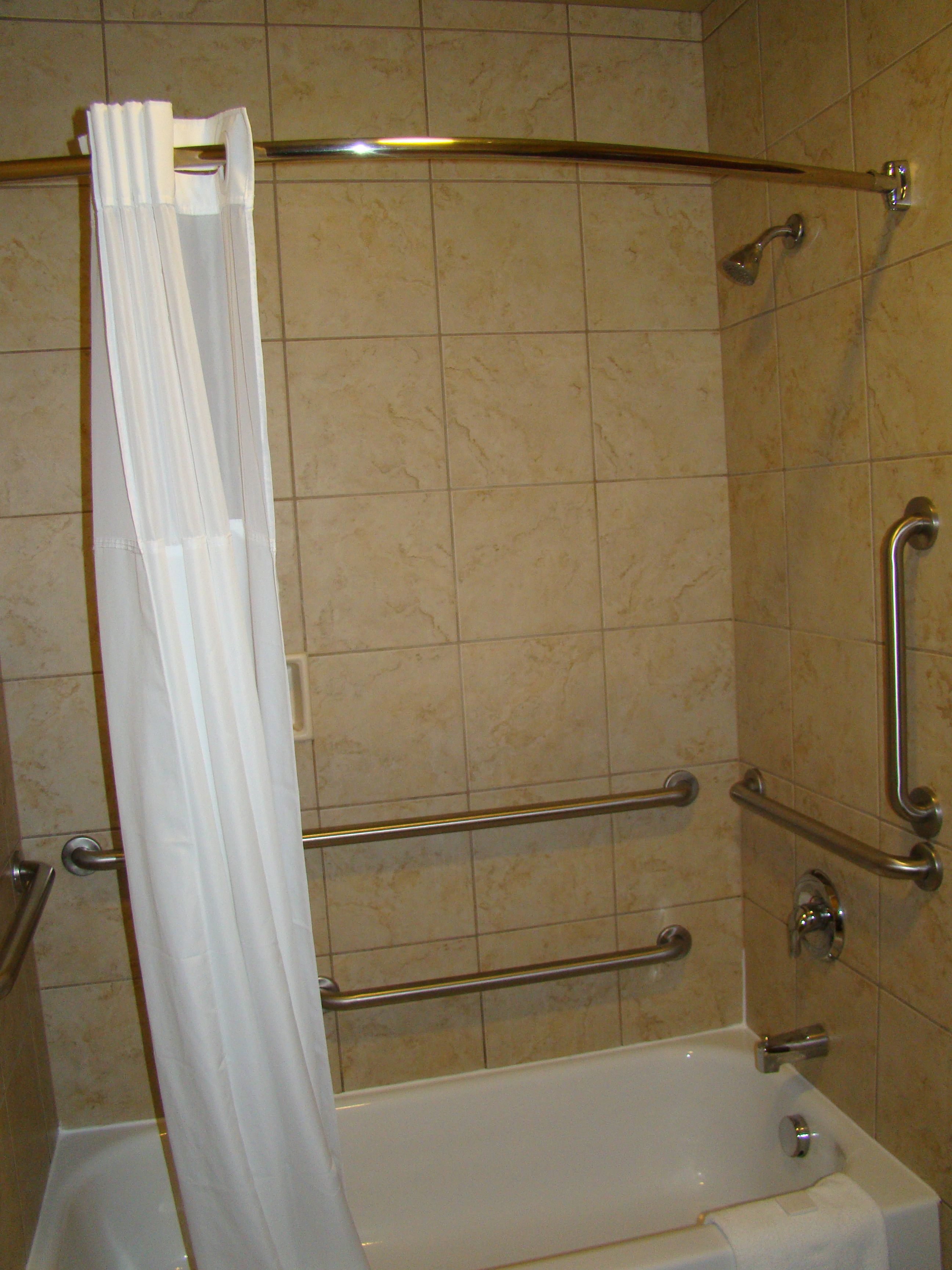 Ein Badezimmer mit Badewanne, Haltegriffen und einer Duschvorhang.