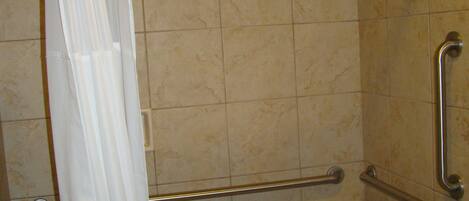 Ein Badezimmer mit Badewanne, Haltegriffen und einer Duschvorhang.