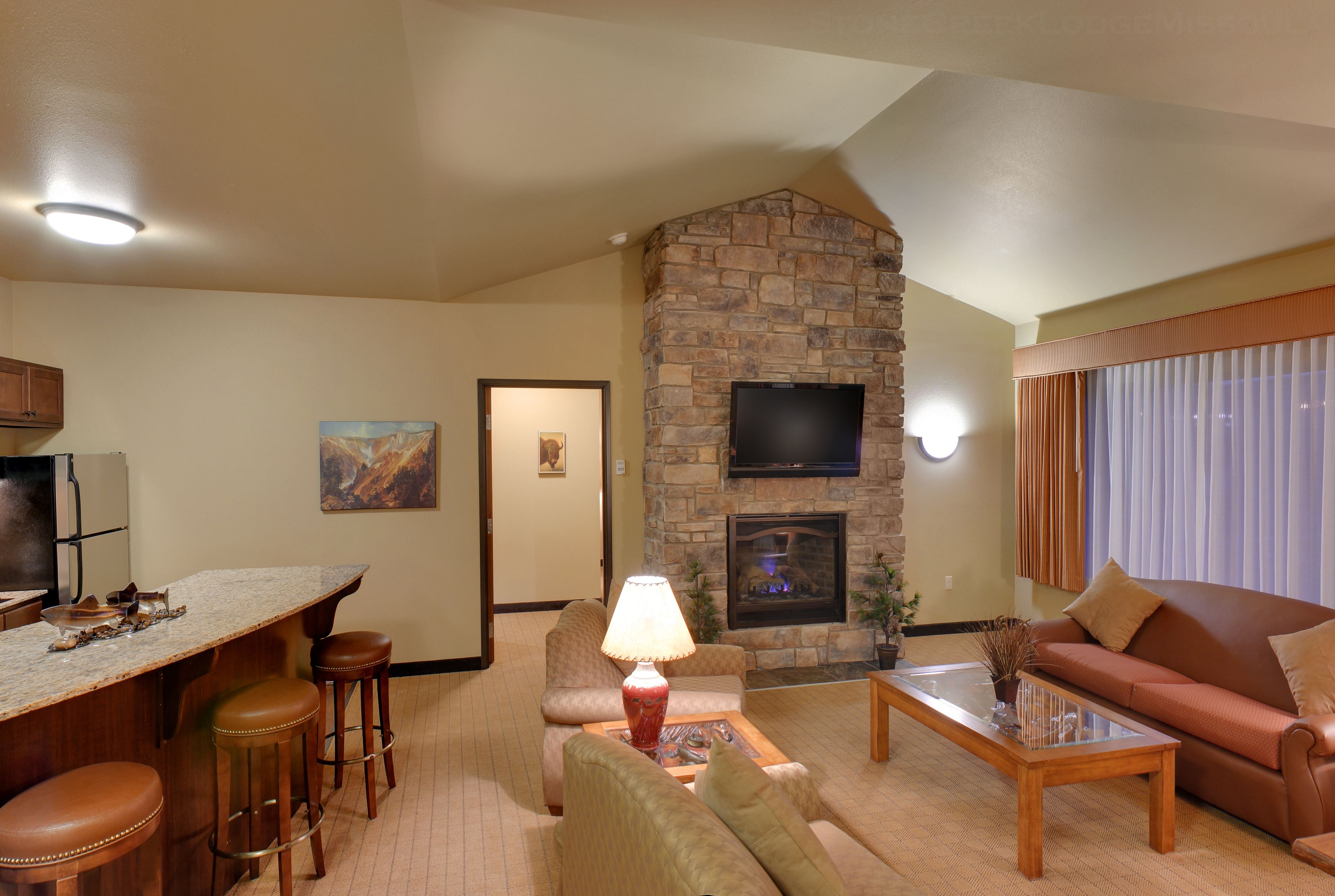 A living room with a stone fireplace, a flat-screen TV, a sofa, and a coffee table.