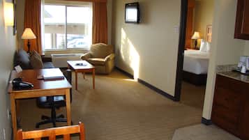 A hotel room with a desk, chair, sofa, armchair, and a bed.