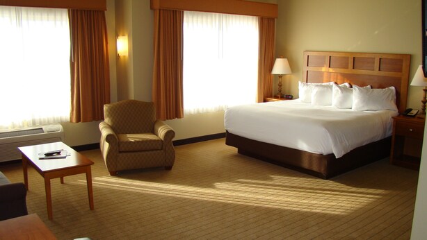 A hotel room with a large bed, a chair, a desk, and a lamp. - StoneCreek Lodge (Missoula)