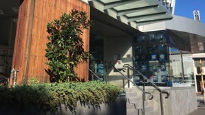 Un edificio moderno con un llamativo letrero 'Quest', fachada de madera y entrada de cristal.