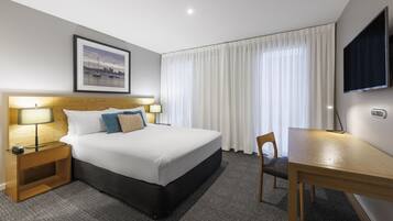A hotel room with a large bed, bedside lamps, a desk, and a TV.