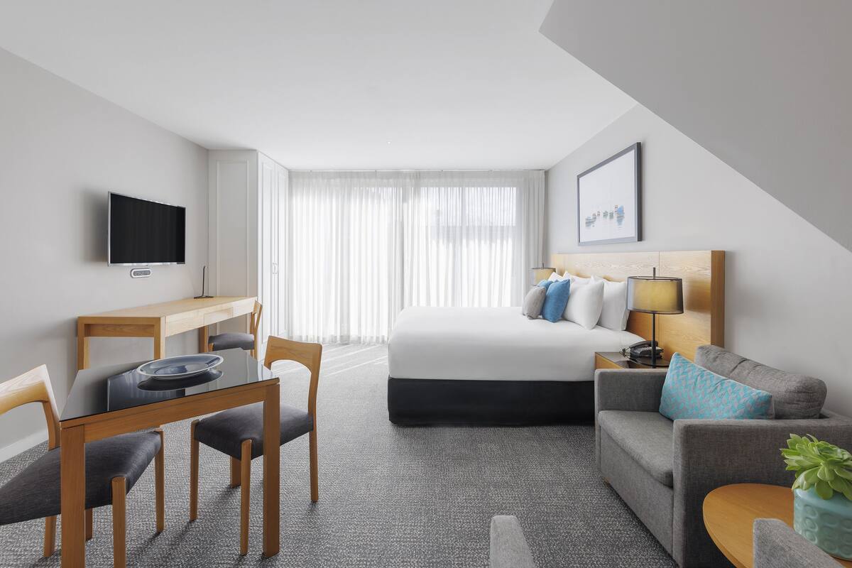 Ett hotellrum med en säng, en soffa, ett skrivbord och en tv.