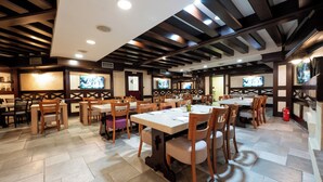 Un restaurante con mesas y sillas de madera, suelo de baldosas e iluminación empotrada.