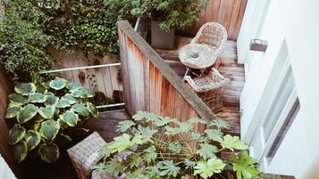 Una terraza de madera con una silla de mimbre y una planta en maceta.